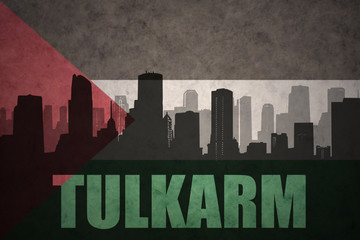 abstract silhouette of the city with text Tulkarm at the vintage palestinian flag background