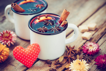 Mulled wine in mugs, red heart, spice and dry flowers.