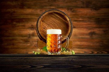 Pint of cold beer and old barrel on wooden background