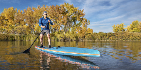 Fototapeta na wymiar stand up paddling in fall colors
