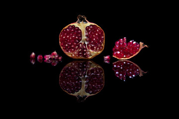 Pomegranate on black reflective background