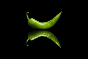 Green pepper on black reflective background