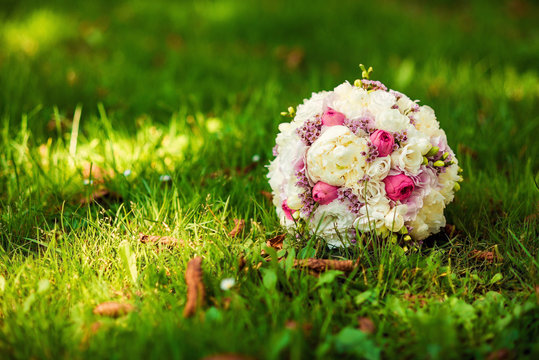 Wedding bridal bouquet of delicate pink and white flowers lying on green grass. wedding concept