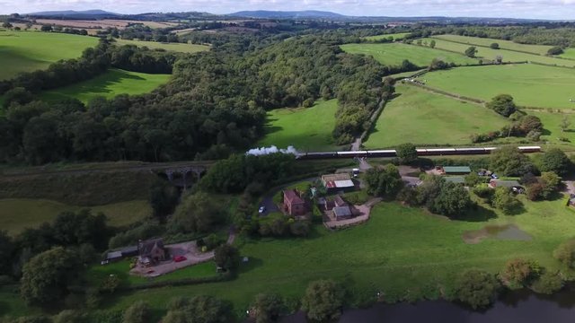 Aerial View Of A Steam Train Passing Country Houses In An English Village.