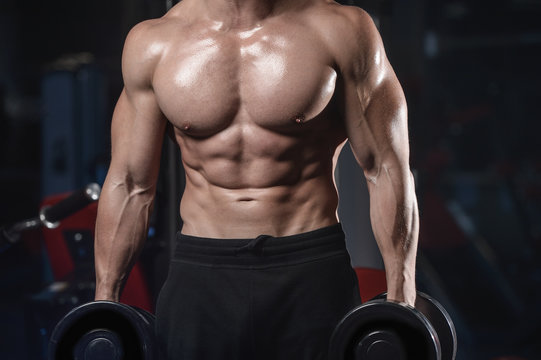 Handsome athletic fitness man posing and trains in the gym.