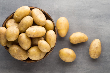 New potato on the bowl, gray background.