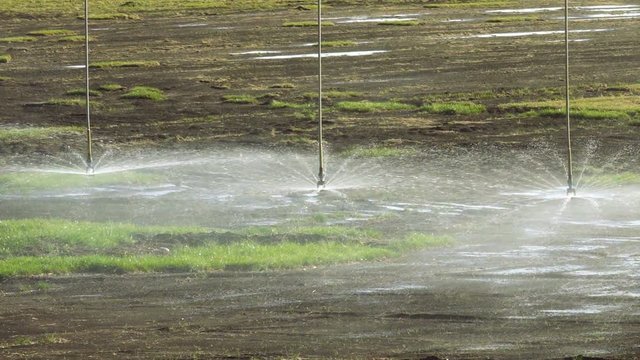 Irrigation system watering a dried-up field for a good harvest, slow motion