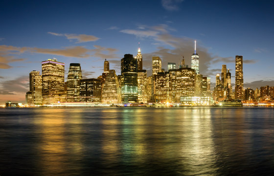 The Downtown Manhattan skyline at sunset with reflections on the East River