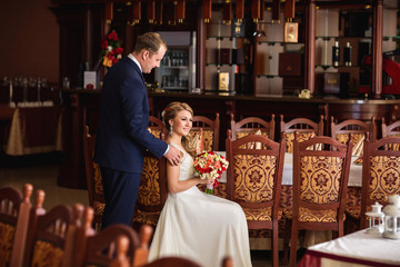 Wedding. Groom gently touch the shoulder of a beautiful bride, who is sitting in a restaurant