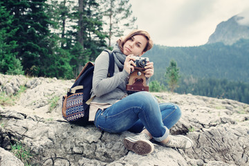 Fototapeta premium Woman traveler with vintage camera sitting on rocks, nature landscape