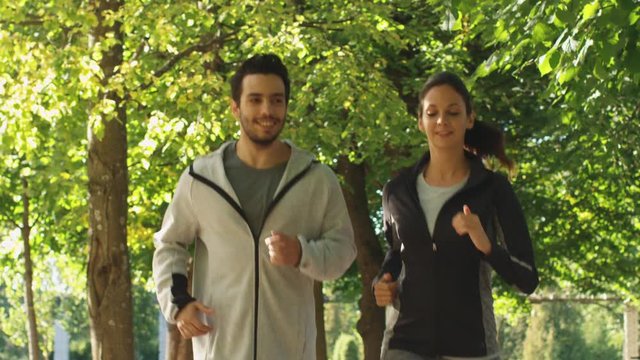 Young Man and Woman Running Together at in Park at Bright Sunny Day. Shot on RED Cinema Camera in 4K (UHD).