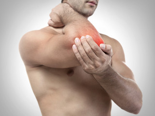 Young man with pain in elbow on grey background