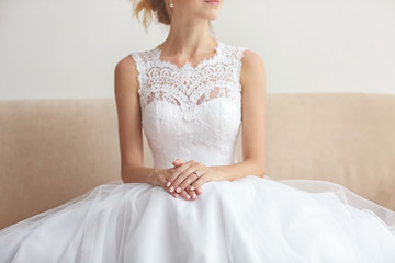 Bride in beautiful wedding gown sitting on sofa