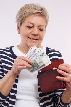 Happy senior female holding wallet with polish currency money, concept of financial security in old age
