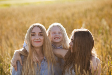 beautiful young mother and her daughters at the wheat field