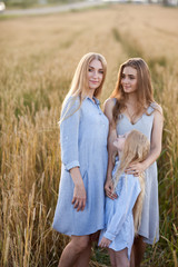 beautiful young mother and her daughters at the wheat field