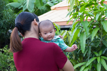 Baby smile happily with holding hands mother in the garden.
