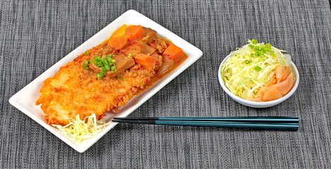 Deep fried dolly fish (Crispy) in Japanese style topped yellow curry with side dish as sliced cabbage and pickled ginger are very delicious