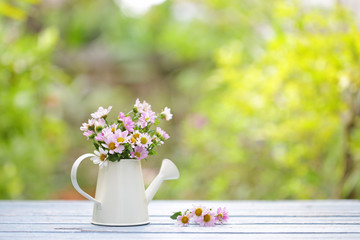 Flowers in vintage water can on wooden table