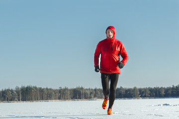 Ultra trail runner wearing red protective sportswear on winter training outdoors
