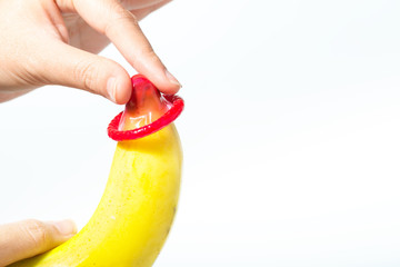 Female hand put condom a banana. Safe sex concept.
