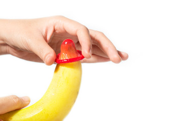 Female hand put condom a banana. Safe sex concept.