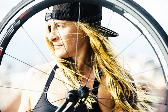 Woman looking through bike wheel.