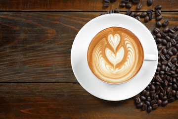 coffee cup  of coffee latte art and coffee beans on old wooden b