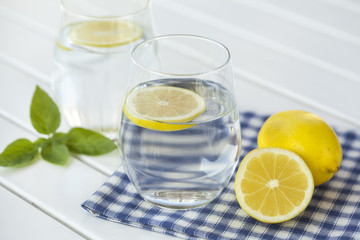 Glass of water with lemon on white background