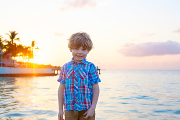 Little kid boy at sunset near ocean