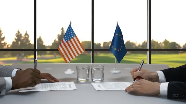 Businessmen in suits signing papers. Flags of USA and EU. Build way to progress. Policy and strategy.