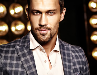 closeup portrait of sexy handsome fashion male model man dressed in elegant suit on black studio lights background