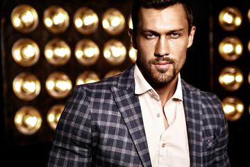 closeup portrait of sexy handsome fashion male model man dressed in elegant suit on black studio lights background