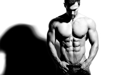 Fototapeta na wymiar Portrait of strong healthy handsome Athletic Man Fitness Model posing near white wall