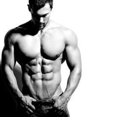 Portrait of strong healthy handsome Athletic Man Fitness Model posing near white wall