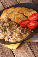 Steak with mushrooms and roasted potatoes close-up. vertical
