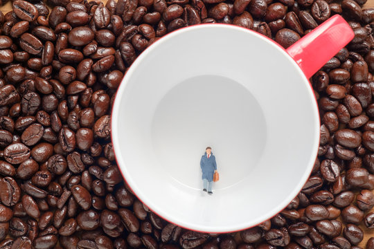 Toy businessman / View of miniature toy, businessman walking in red coffee cup on coffee bean background.