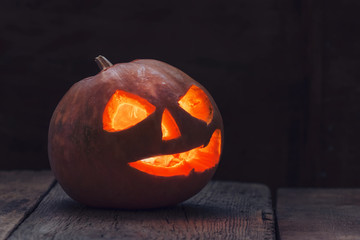 Halloween pumpkin Jack-o-Lantern on the dark wood background, se