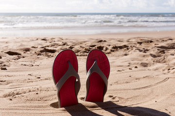 Travel background with a pair flip flops in the sand of a beach