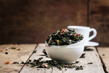 Dry Ceylon green tea on a vintage wooden background, selective f