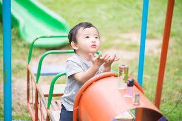 Fototapeta na wymiar Young Asian boy play a iron train swinging at the playground und