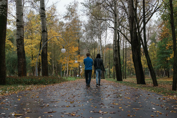 Fototapeta premium Loving couple walking along autumn park. View from the back