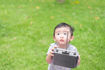 Little Asian kid holding a radio remote control (controlling han