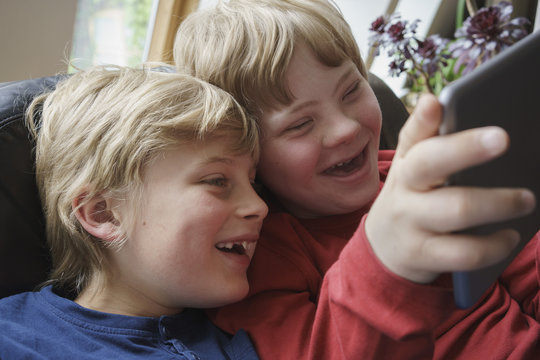 Close-up of happy brothers using digital tablet at home