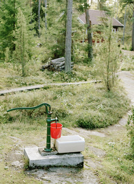 Isolated hand pump with trees and house in background