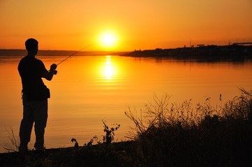 Fisherman on the sunset background