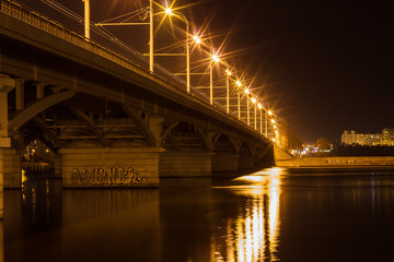 Obraz premium Bridge, city lights reflected in the water. Long exposure