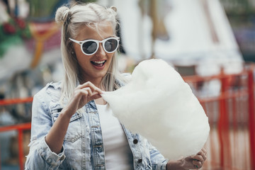 Fashionable young woman wearing sunglasses while eating cotton candy outdoors