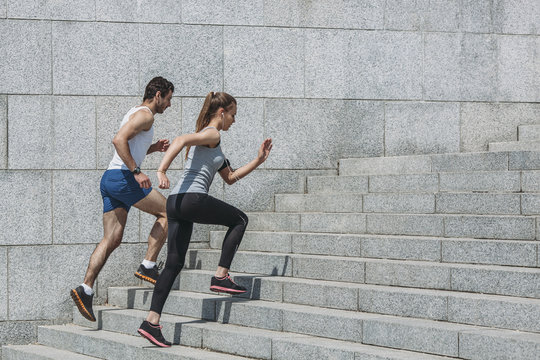 Determined friends jogging up steps by wall
