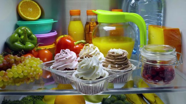 Sweet cakes in the open refrigerator. Products in the refrigerator.